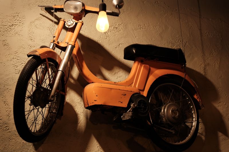 Cyclomoteur orange contre un mur à la lumière chaude