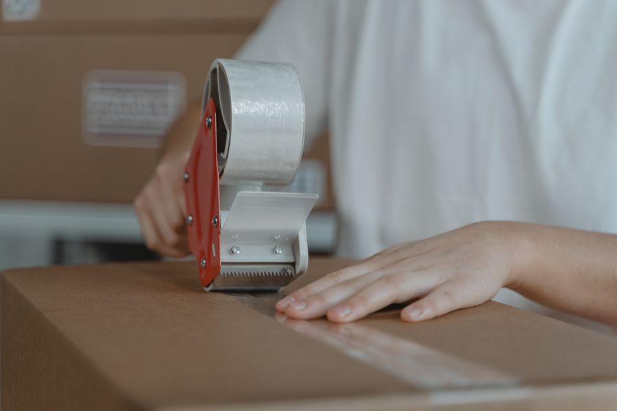 Mains fermant un carton avec du ruban adhésif